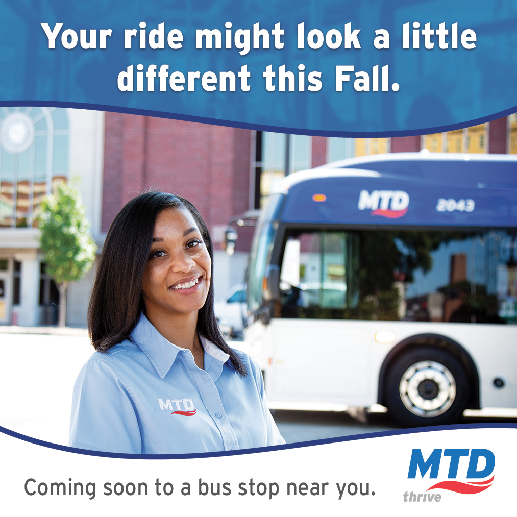 An MTD bus driver smiling and standing in front of a rebranded MTD bus.